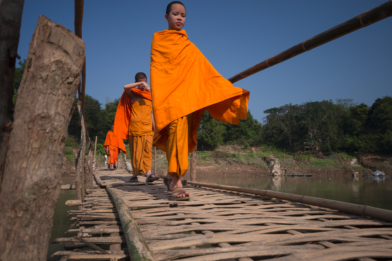 Novices traversant un pont de bois au-dessus du Mékog à Luang Prabang, Laos