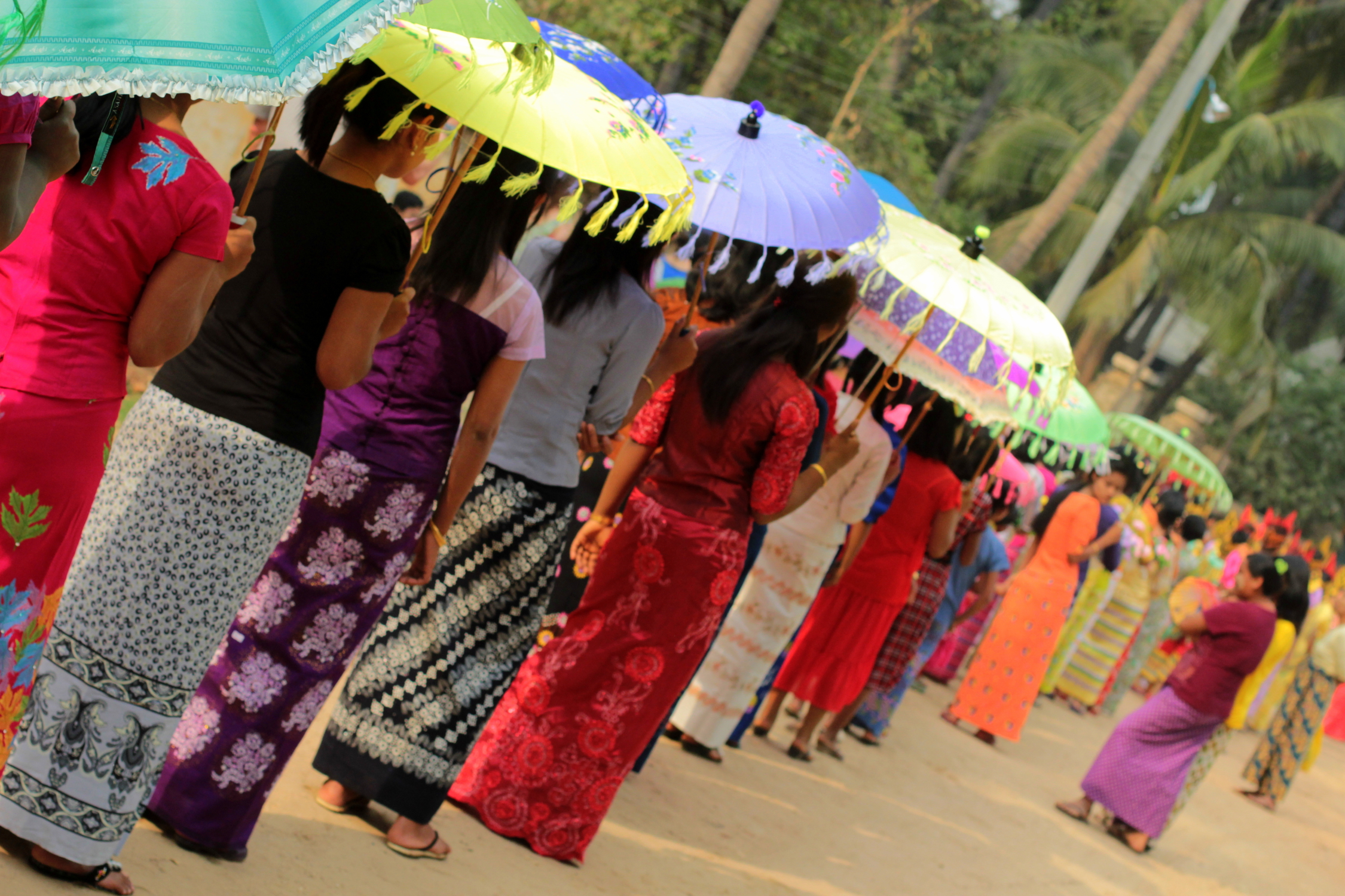 Femmes en longyi et ombrelles à la cérémonie de Shinbyu, Bagan, Birmanie