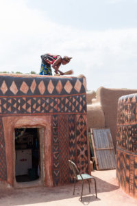 Femme se préparant à passer une couche de vernis sur les motifs peints de sa case, cour royale, Tiébélé, Burkina Faso