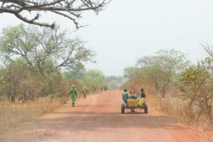 Carriole tirée par un âne et piétons sur la piste rouge entre Nazinga et Bobo Dioulasso, Burkina Faso