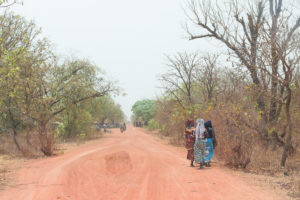 Femmes vêtues de wax sur le bord de la piste rouge entre Nazinga et Bobo Dioulasso, Burkina Faso