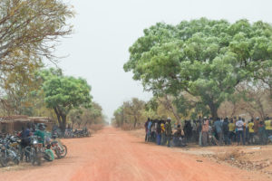 Attroupement d'hommes sous un arbre au bord de la piste entre Nazinga et Bobo Dioulasso, Burkina Faso