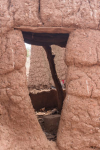 Ouverture sur l'intérieur d'une case et petite poule dans le fond, village Lobi de Sansana, Burkina Faso