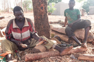 Sculpteur sur bois en train de façonner une figurine avec un maillet, village d'artisans Lobi, Burkina Faso