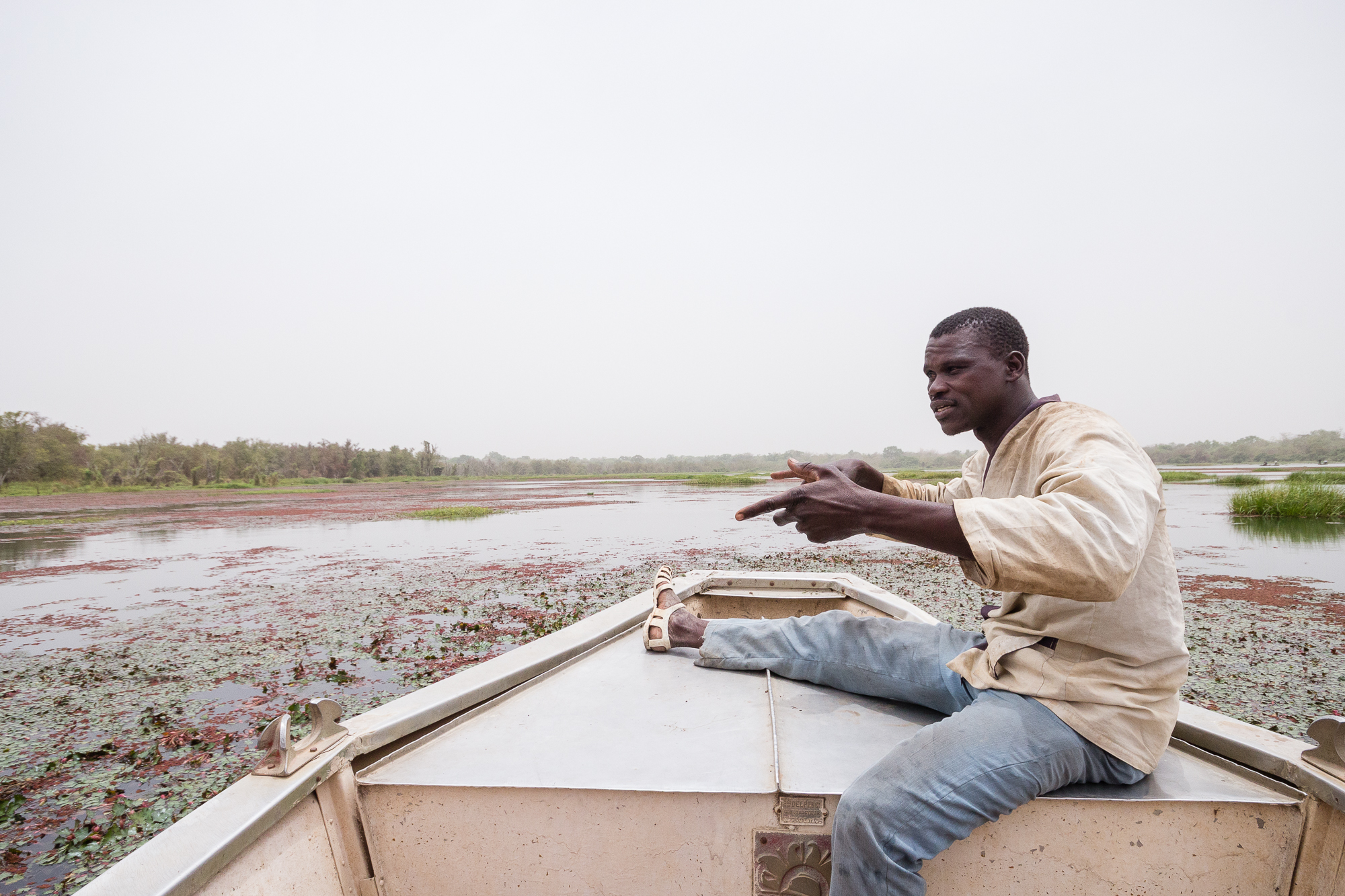 Homme en pleine discussion assis à l'avant d'une barque sur la mare de Bala, Burkina Faso
