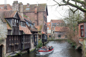 Touristes en barque sur les canaux de Bruges bordés de maisons médiévales, Belgique