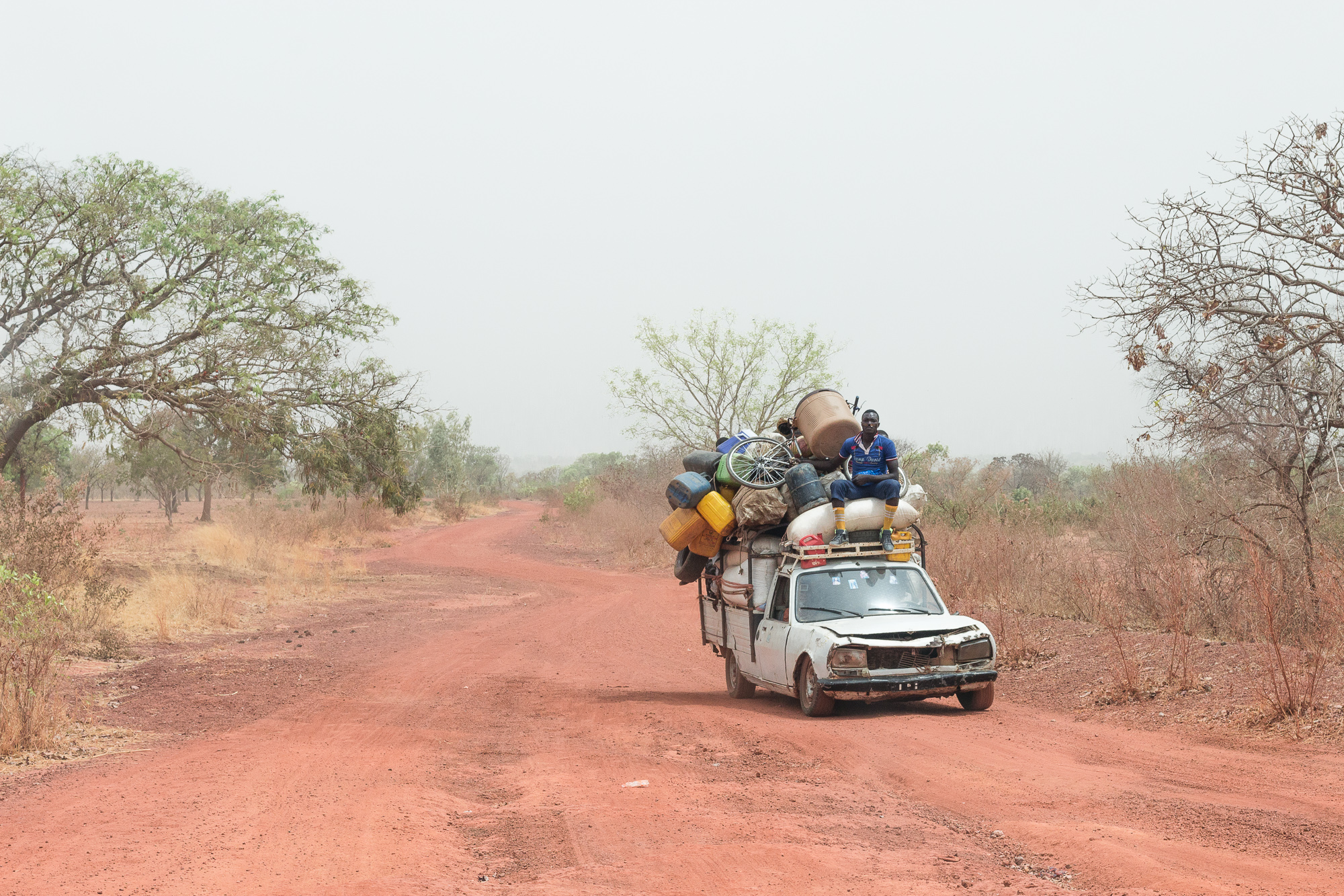 Vieille voiture surchargée et homme sur le toit, sur la route, Burkina Faso