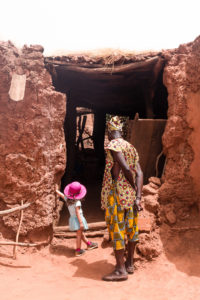 Fillette et habitant de Koumi regardant l'entrée d'une case, village traditionnel Bobo de Koumi, Burkina Faso