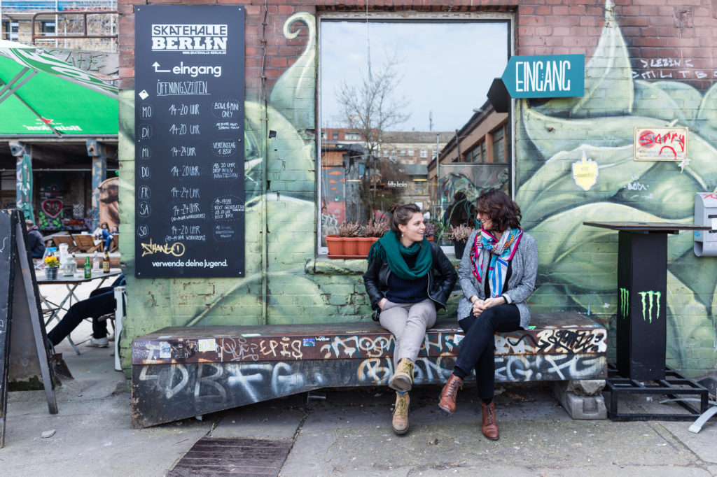 Femmes sur un banc devant une fresque à Berlin